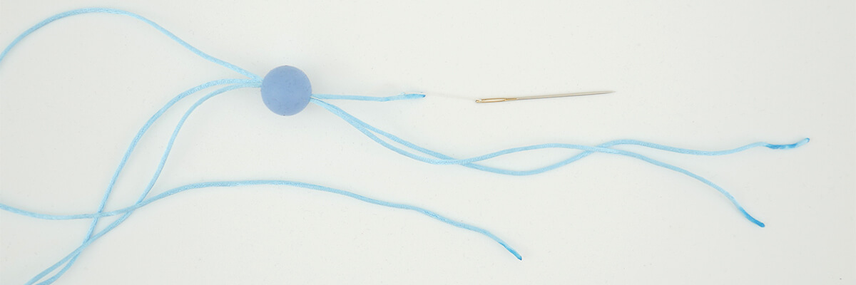 Istruzioni per creare il supporto da muro di perline: infilare le perline di silicone su 4 fili con l'aiuto per l’infilatura